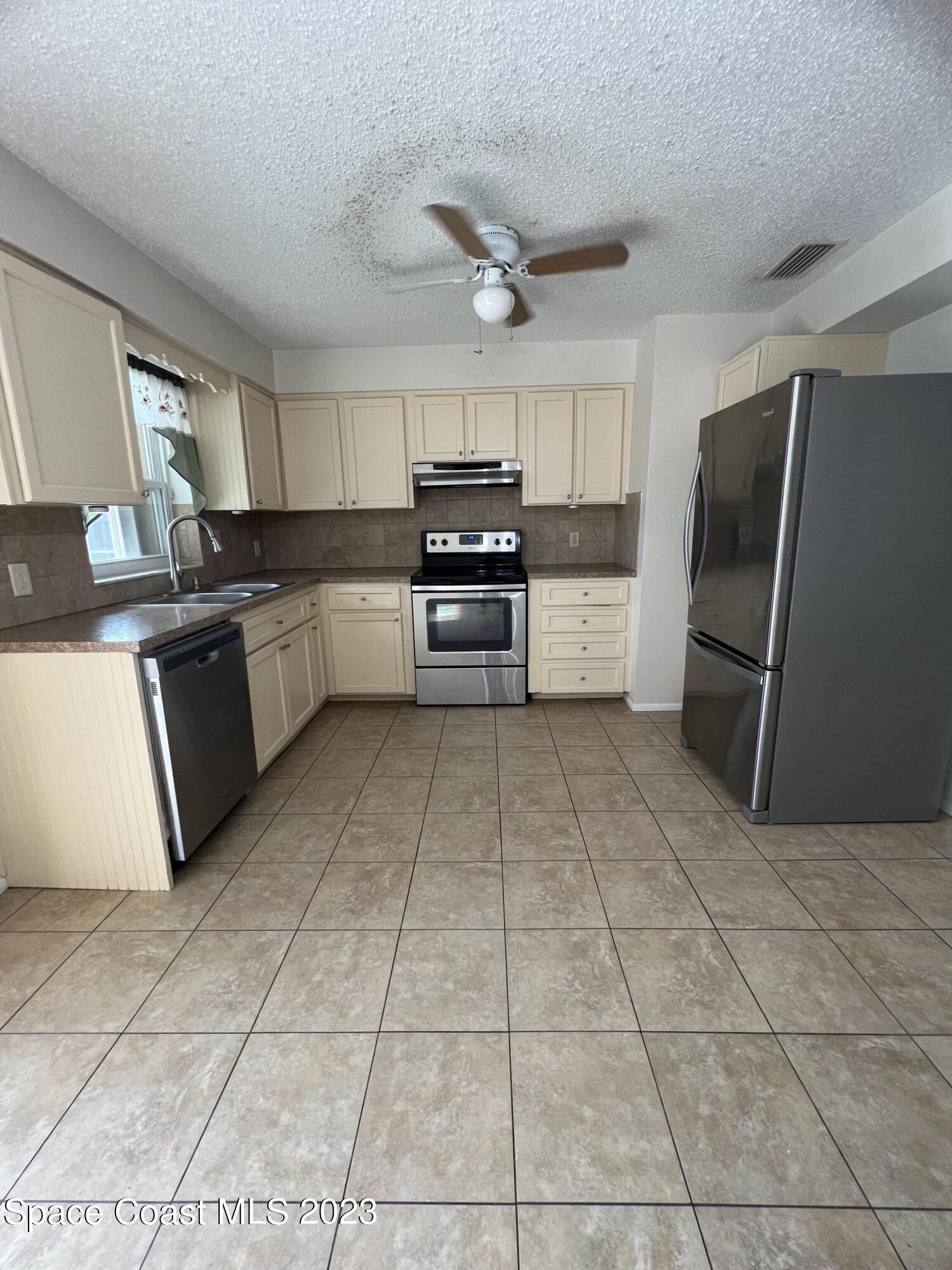 283 Fecco Street Cocoa, FL 32927 - Photo 6 of 25 a kitchen with granite countertop a refrigerator and a stove top oven