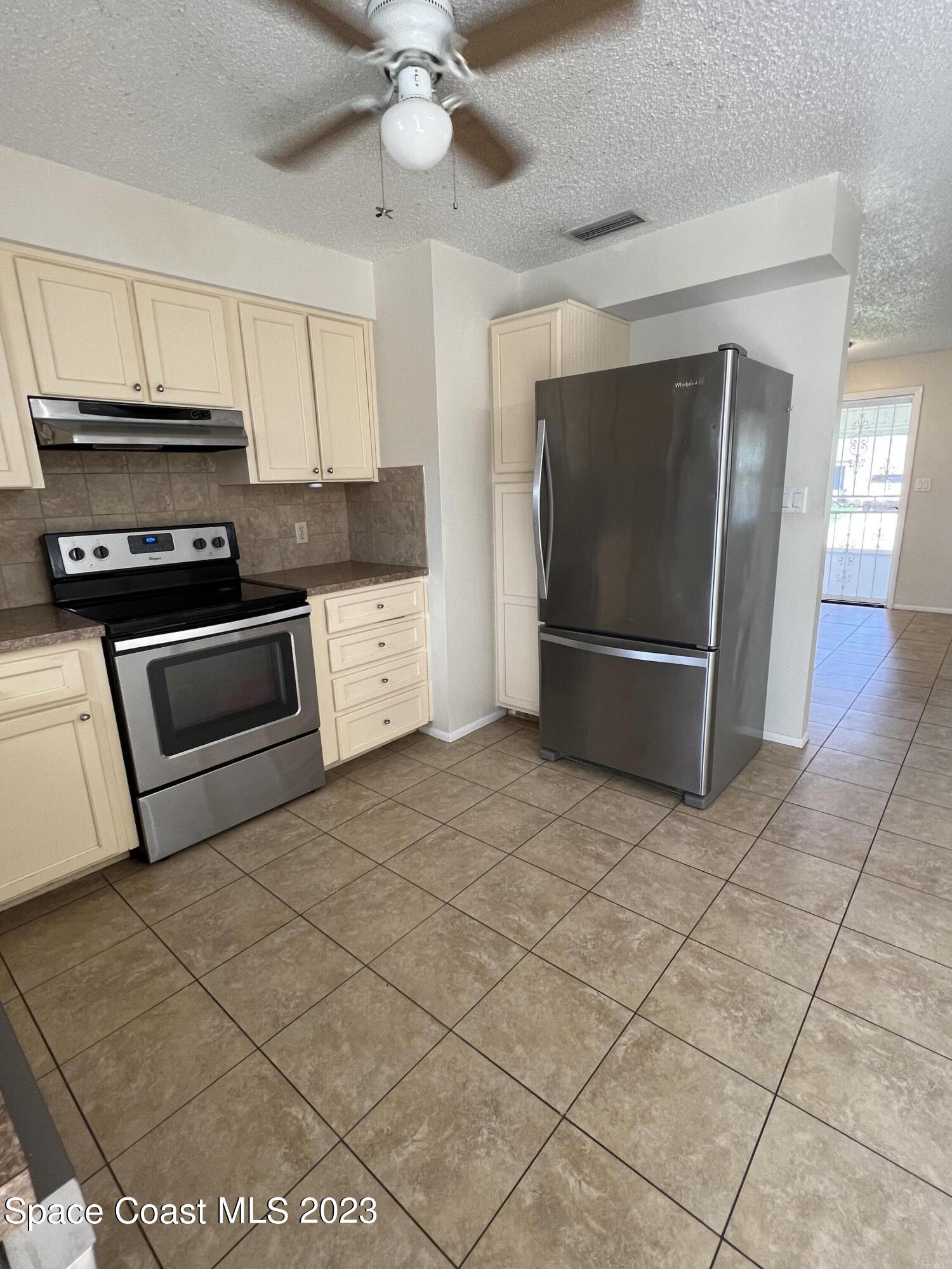 283 Fecco Street Cocoa, FL 32927 - Photo 8 of 25 a kitchen with stainless steel appliances granite countertop a refrigerator a stove and white cabinets with wooden floor
