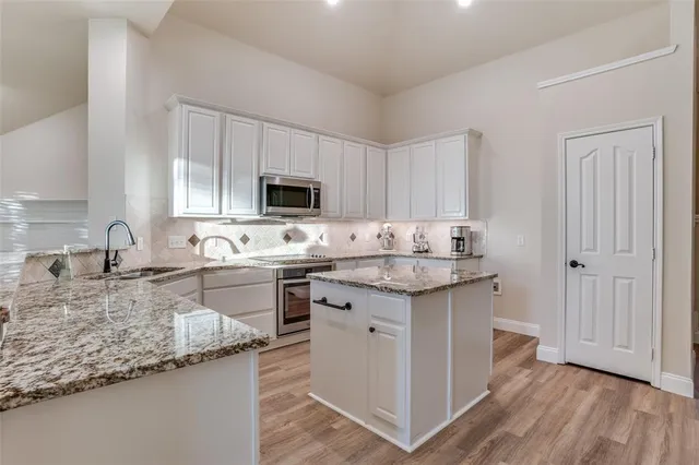 a kitchen with granite countertop a sink stove and cabinets