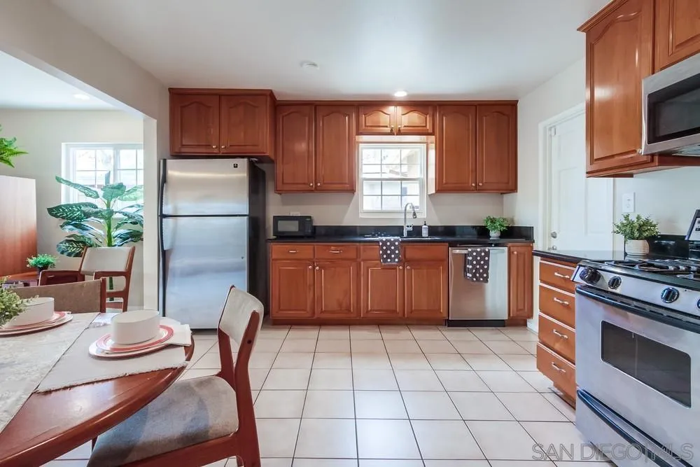 4441 Appleton Street San Diego, CA 92117 - Photo 7 of 29 a kitchen with stainless steel appliances granite countertop a stove a sink dishwasher a refrigerator with a dining table and chairs