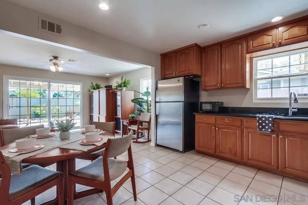 4441 Appleton Street San Diego, CA 92117 - Photo 8 of 29 a kitchen with stainless steel appliances granite countertop a refrigerator a sink dishwasher a dining table and chairs with wooden floor