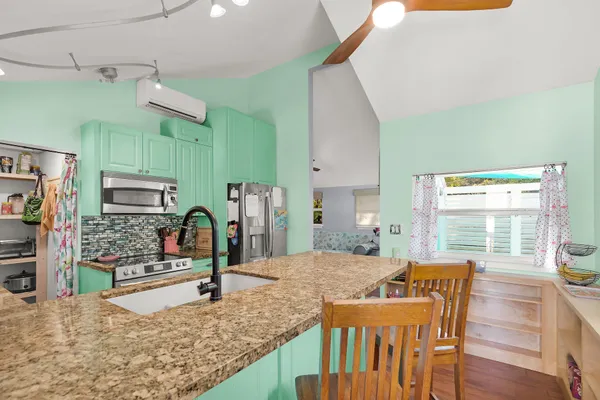 a kitchen with stainless steel appliances kitchen island granite countertop a table chairs in it and wooden floors