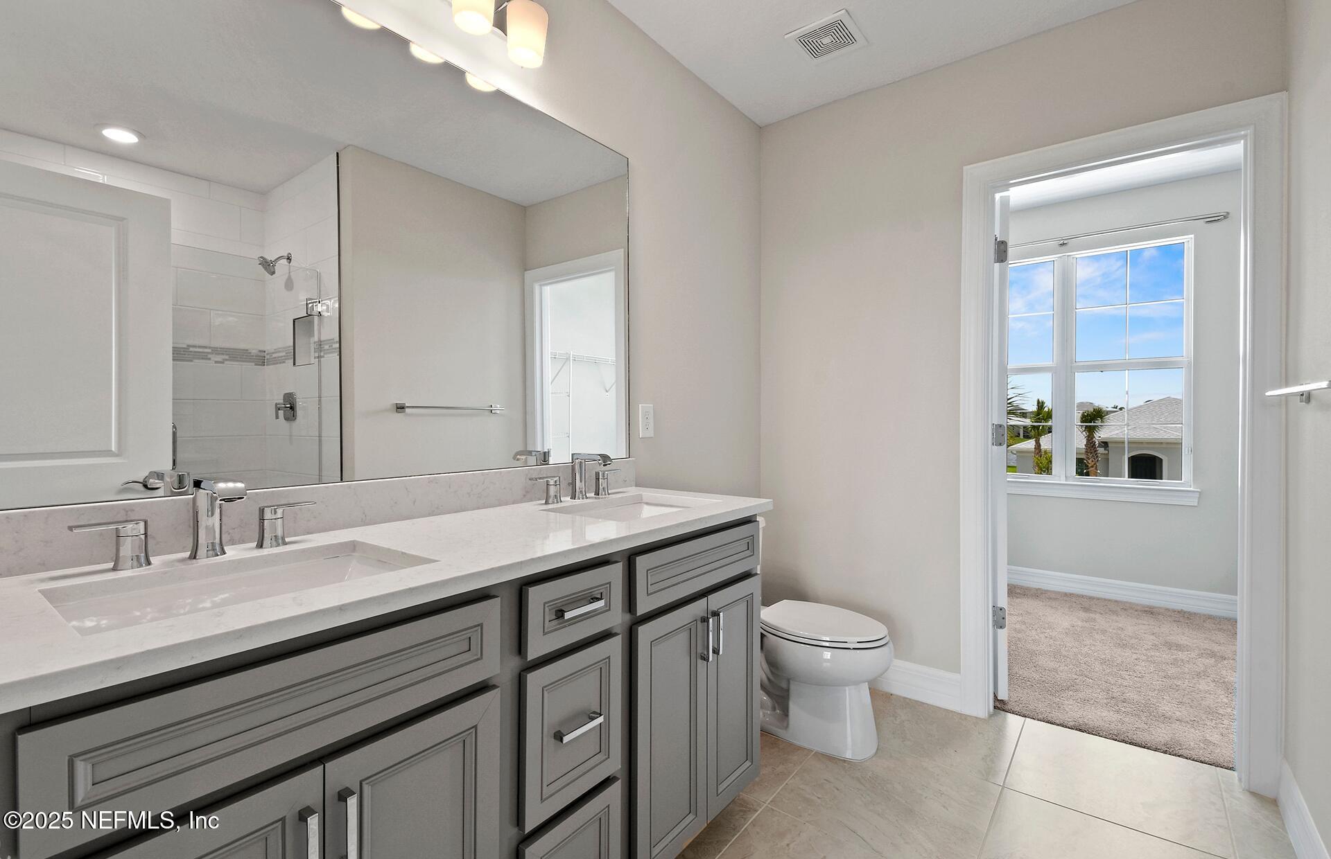 45 Blind Oak Circle St. Augustine, FL 32095 - Photo 9 of 18 a bathroom with a granite countertop sink a toilet and a mirror