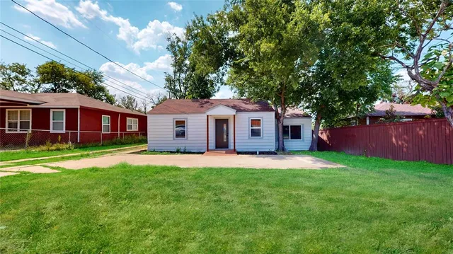a front view of a house with a garden and trees