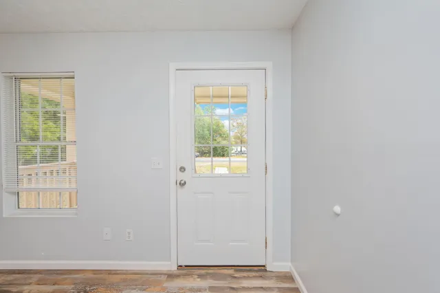 a view of an empty room with wooden floor and windows