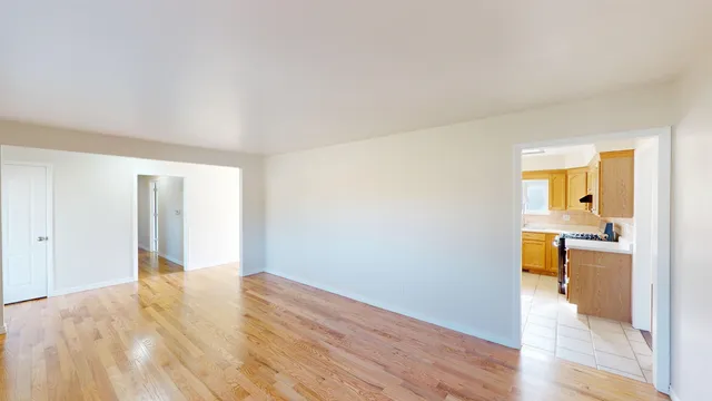 a view of a room with wooden floor and a kitchen