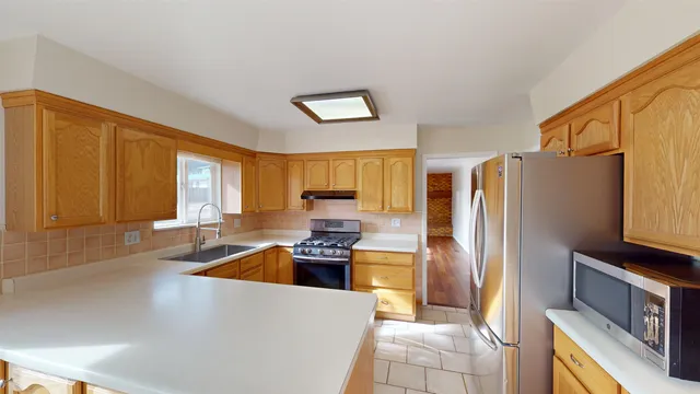 a kitchen with stainless steel appliances granite countertop a refrigerator a stove and a sink with large window