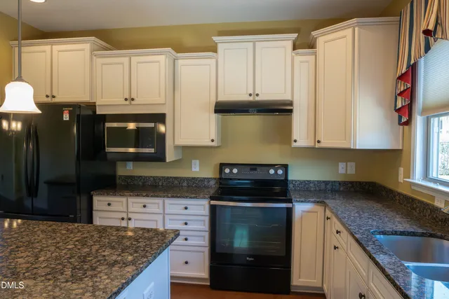 a kitchen with stainless steel appliances granite countertop a stove a sink and a microwave
