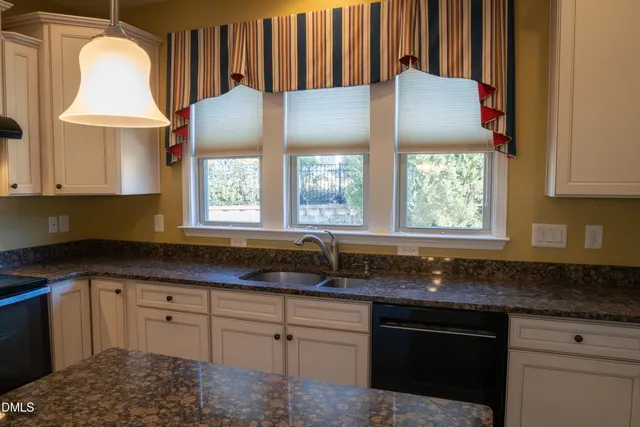 a kitchen with granite countertop a sink a window stainless steel appliances and cabinets