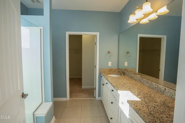 a spacious bathroom with a granite countertop sink and a mirror