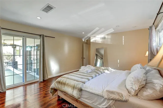 a bedroom with a large bed and wooden floor