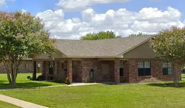 a view of a house next to a yard with big trees