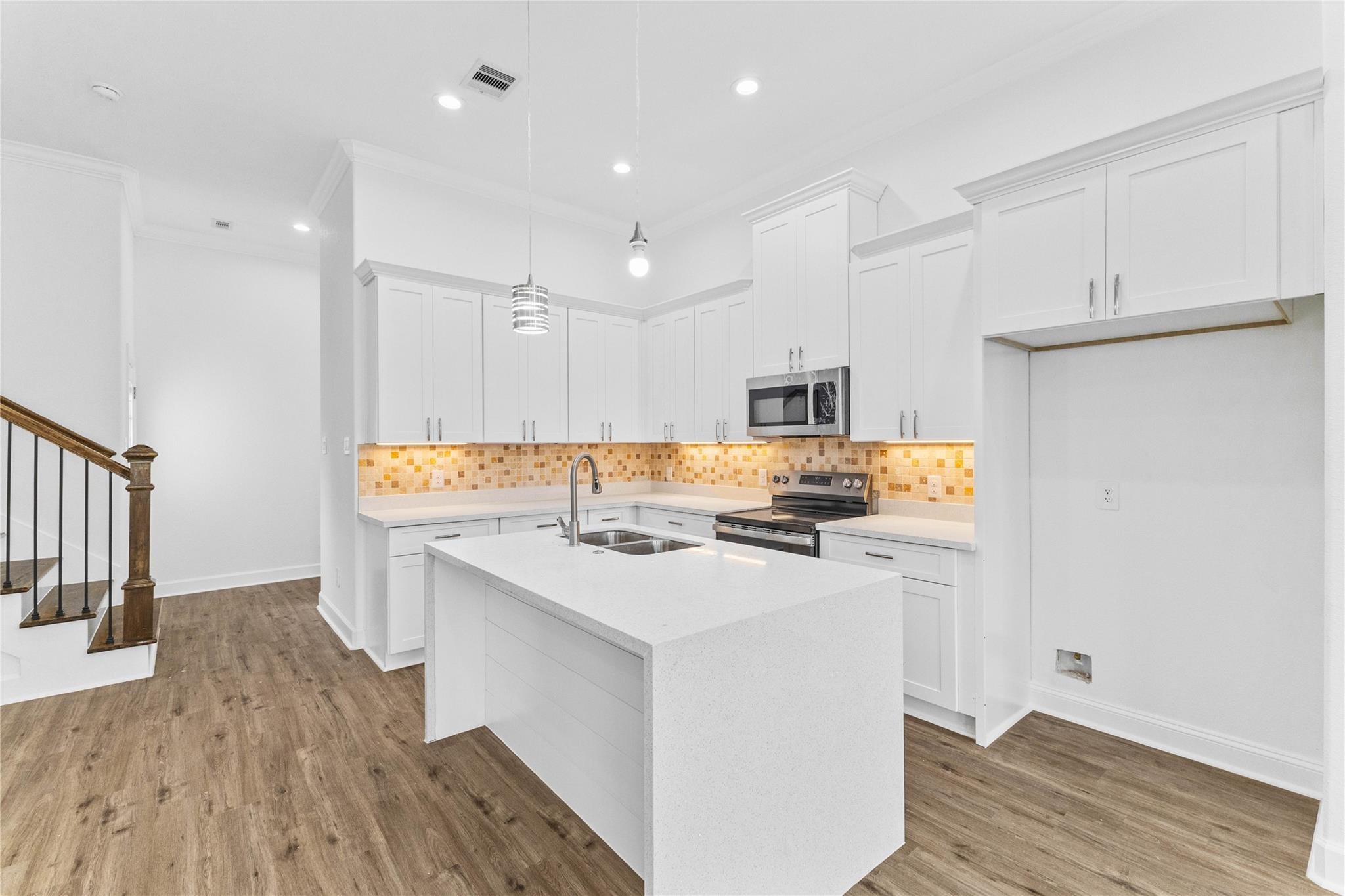 7805 Farnsworth Street, Unit B Houston, TX 77022 - Photo 12 of 26 a kitchen with a sink a stove a refrigerator and white cabinets with wooden floor