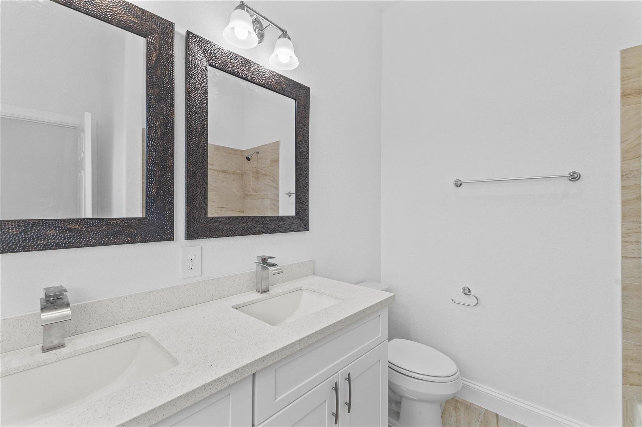 7805 Farnsworth Street, Unit B Houston, TX 77022 - Photo 9 of 26 a bathroom with a toilet a sink a mirror and vanity