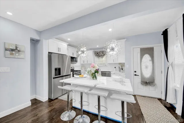 a kitchen with stainless steel appliances a dining table chairs refrigerator and sink