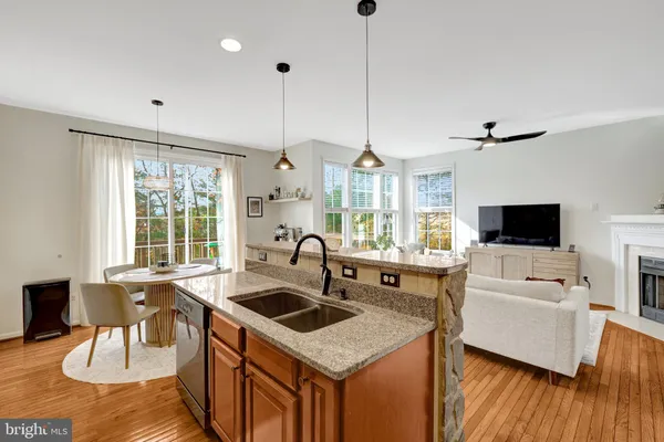 a kitchen with stainless steel appliances granite countertop a sink a stove and a wooden floor