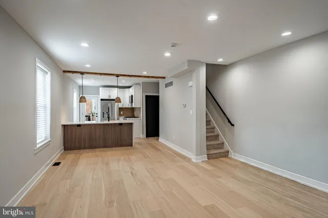 a view of kitchen and empty room with wooden floor