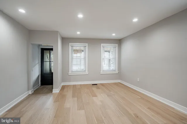 a view of an empty room with wooden floor and window