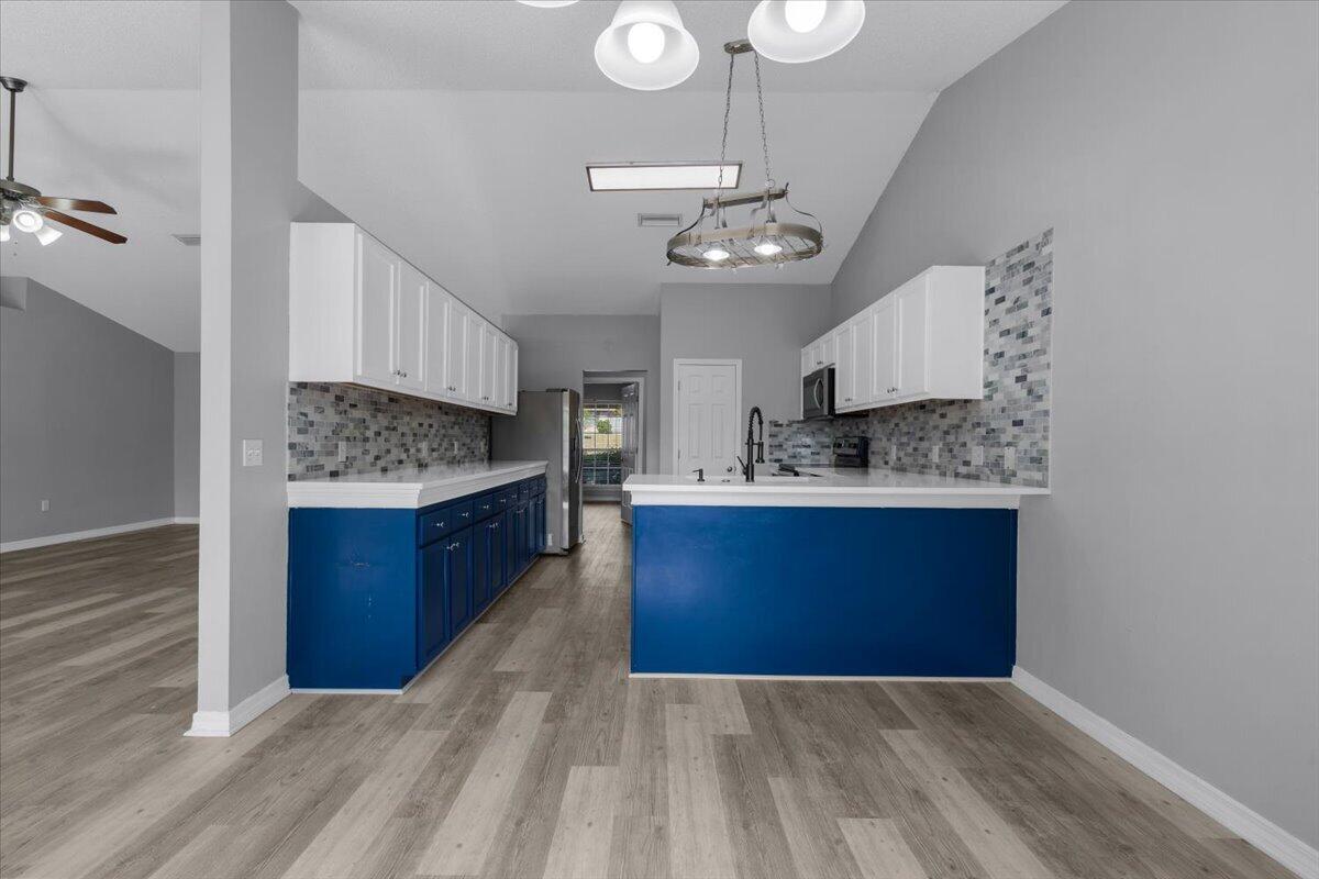 427 Triton Street Crestview, FL 32536 - Photo 9 of 43 a large kitchen with stainless steel appliances kitchen island granite countertop a stove a sink dishwasher and a wooden cabinets