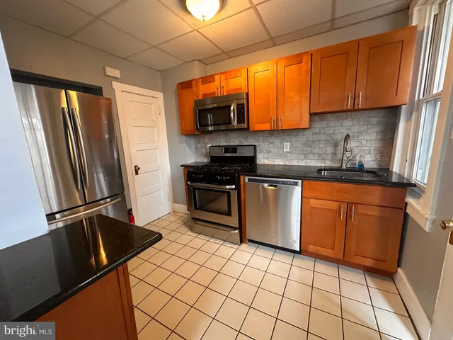 a kitchen with stainless steel appliances a sink cabinets and a window