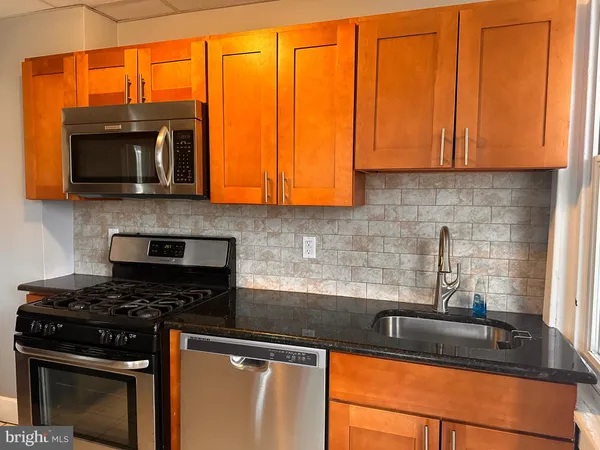 a kitchen with granite countertop wooden cabinets and a stove top oven