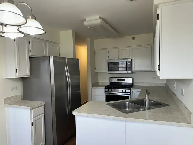 a kitchen with stainless steel appliances granite countertop a refrigerator a stove a sink and a microwave