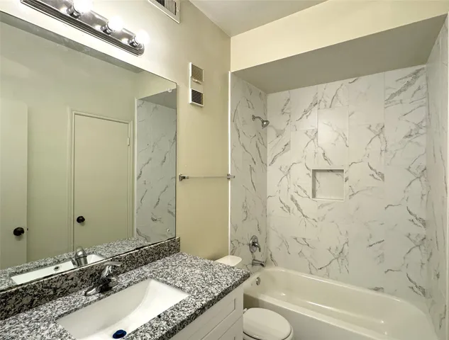 a bathroom with a granite countertop sink and a bathtub