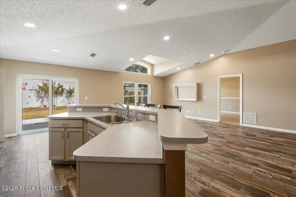 an empty room with wooden floor chandelier fan and windows