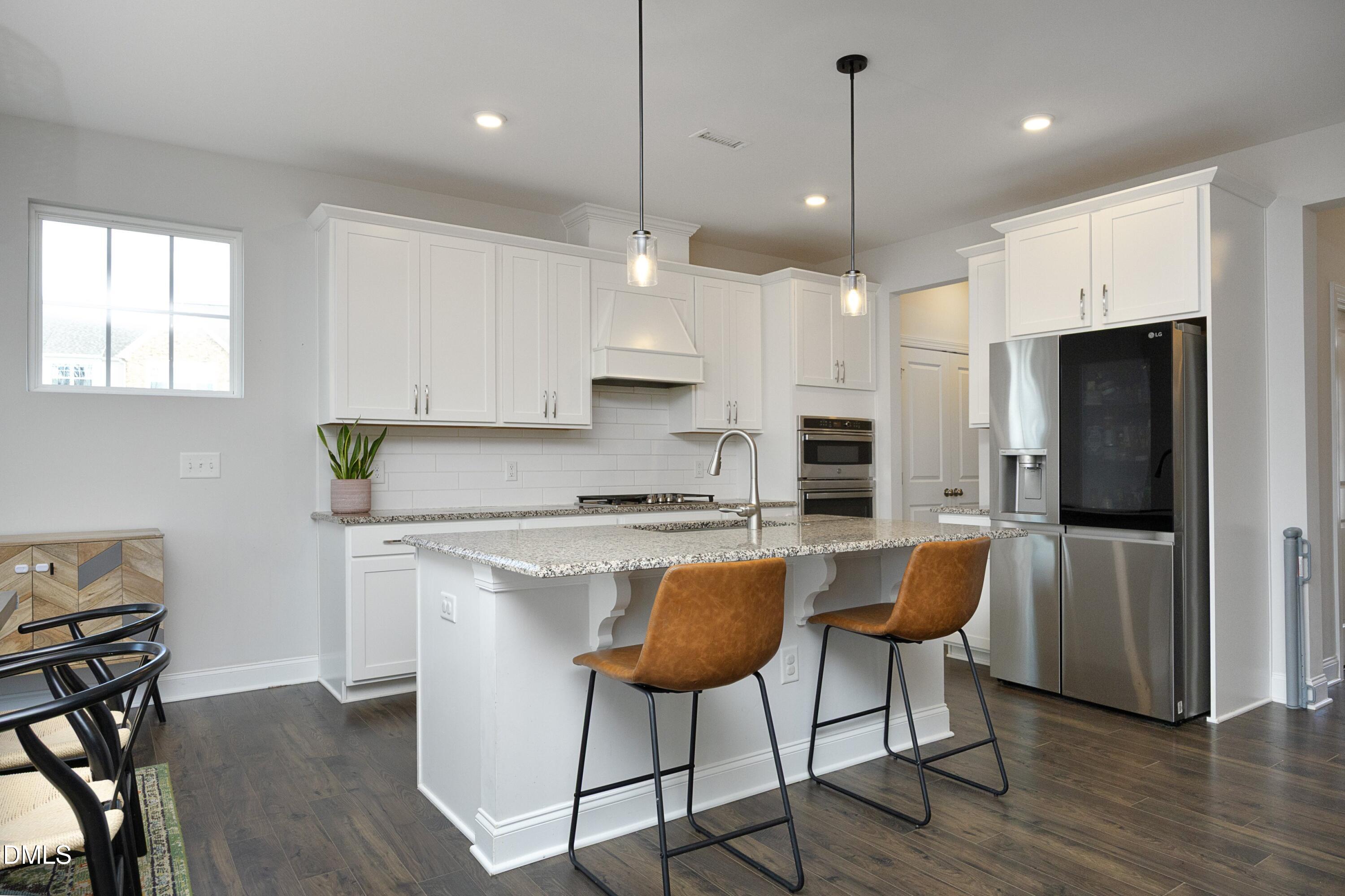 500 Ressler Street Holly Springs, NC 27540 - Photo 2 of 37 a kitchen with stainless steel appliances granite countertop a stove a refrigerator a kitchen island a dining table and chairs