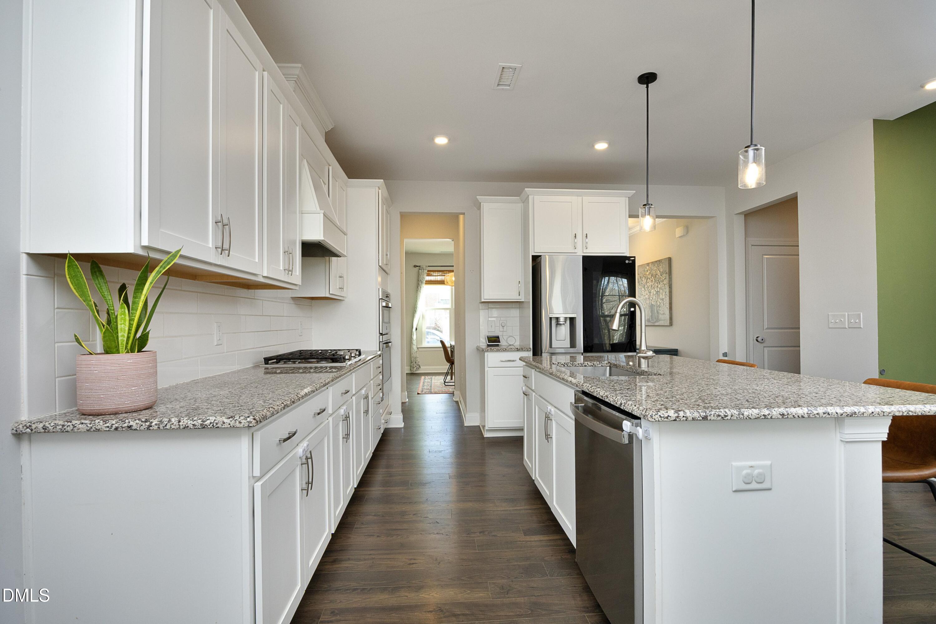 500 Ressler Street Holly Springs, NC 27540 - Photo 4 of 37 a kitchen with granite countertop kitchen island stainless steel appliances a sink a counter top space cabinets and a potted plant