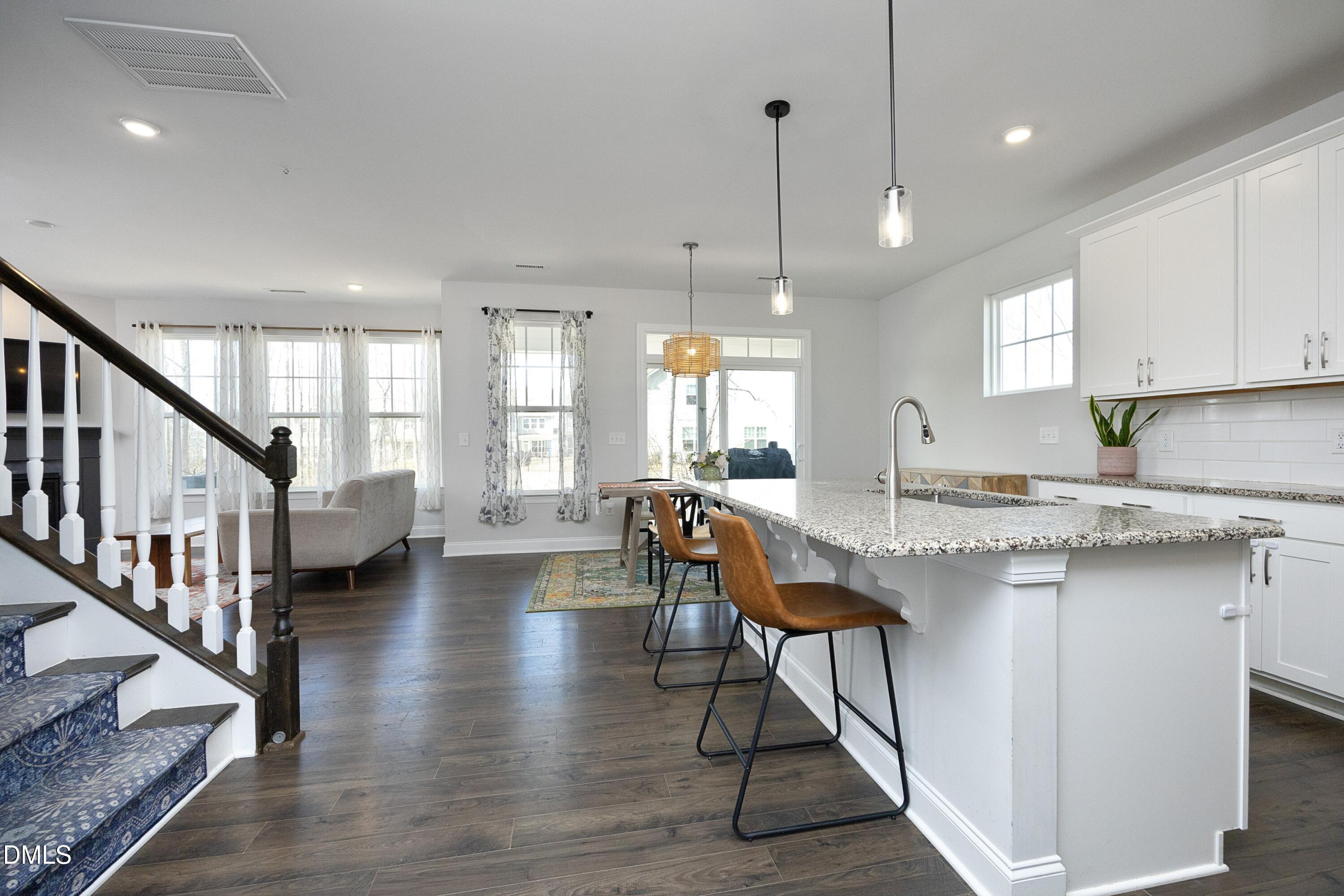 500 Ressler Street Holly Springs, NC 27540 - Photo 6 of 37 a kitchen with stainless steel appliances granite countertop a stove a sink dishwasher a refrigerator and a dining table with wooden floor