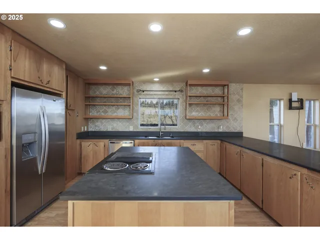 a kitchen with kitchen island a counter top space a sink stainless steel appliances and cabinets