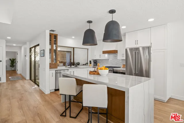 a kitchen with stainless steel appliances granite countertop a refrigerator a sink dishwasher a stove with wooden floor