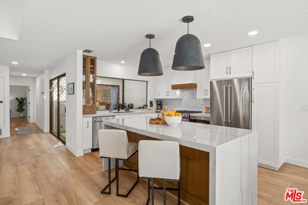 a kitchen with stainless steel appliances granite countertop a refrigerator a sink dishwasher a stove with wooden floor