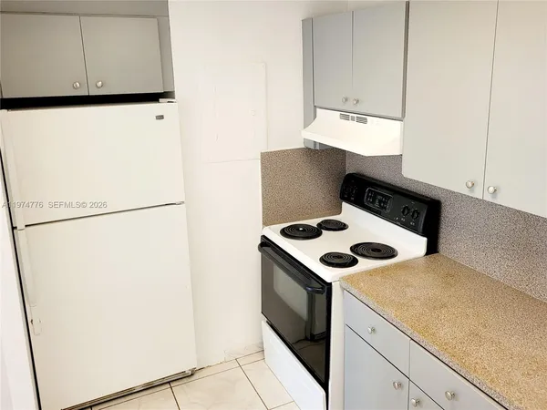 a view of kitchen island with a sink a stove and a refrigerator