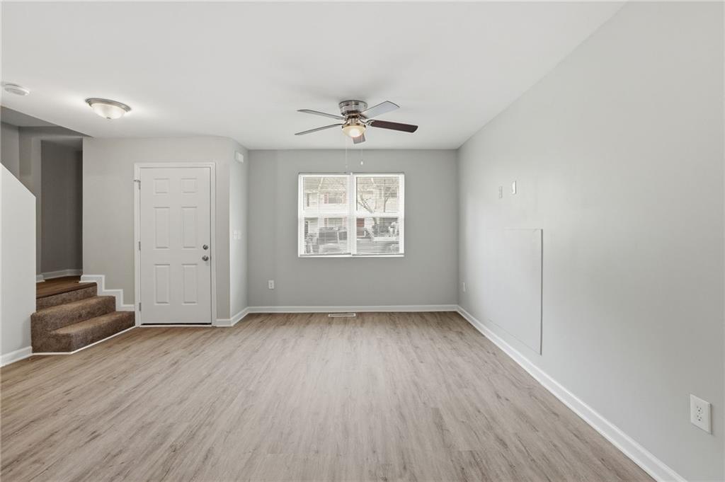 6981 Flagstone Drive Austell, GA 30168 - Photo 9 of 34 an empty room with wooden floor chandelier fan and windows