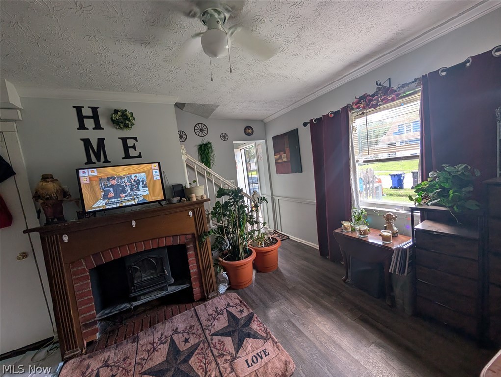 15321 Ridpath Avenue Cleveland, OH 44110 - Photo 23 of 34 Living area featuring a brick fireplace with a wood mantle, wood-finish flooring, crown molding, and a ceiling fan