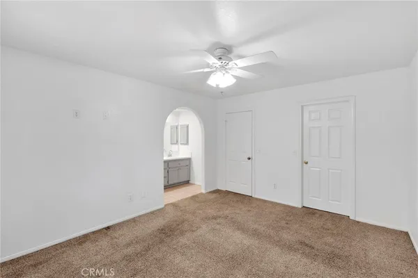 an empty room with chandelier fan and windows