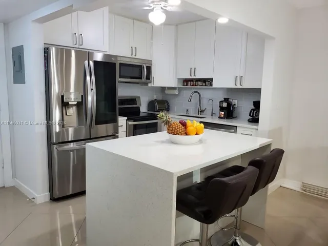 a kitchen with stainless steel appliances a refrigerator a sink a stove a table and chairs