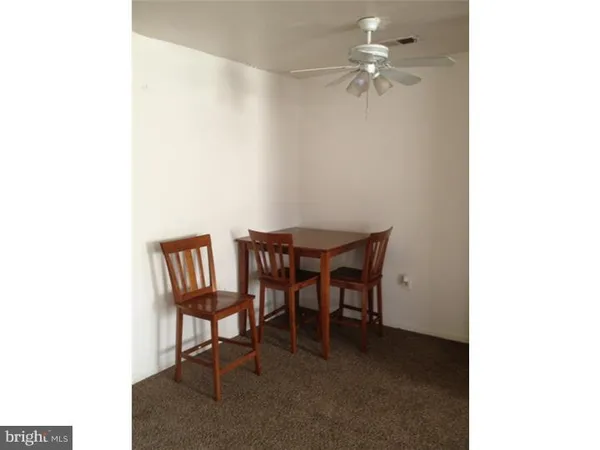 a dining room with furniture and a chandelier fan