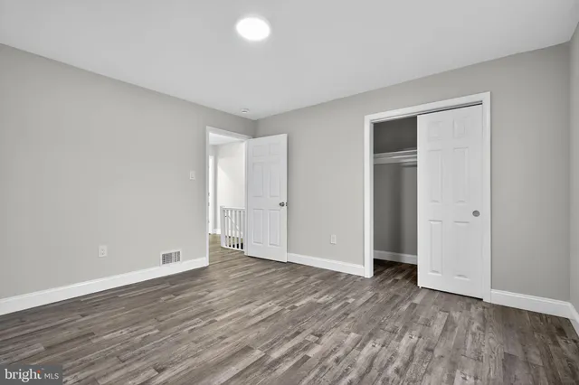 a view of an empty room with wooden floor and closet