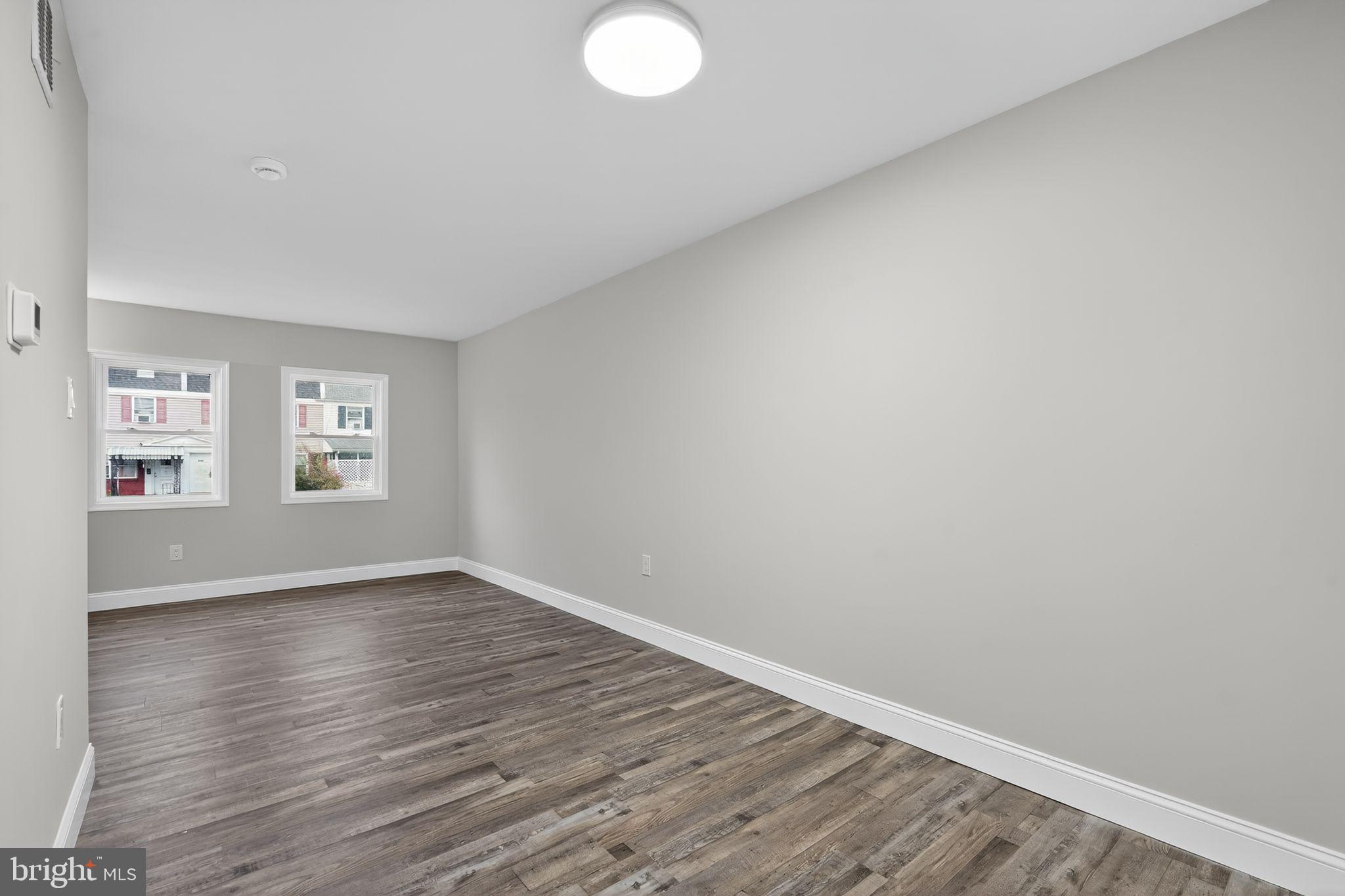 5706 Mitchell Road Levittown, PA 19057 - Photo 15 of 19 a view of an empty room with wooden floor and a window