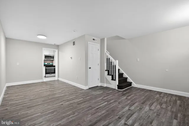 a view of an empty room with wooden floor and stairs