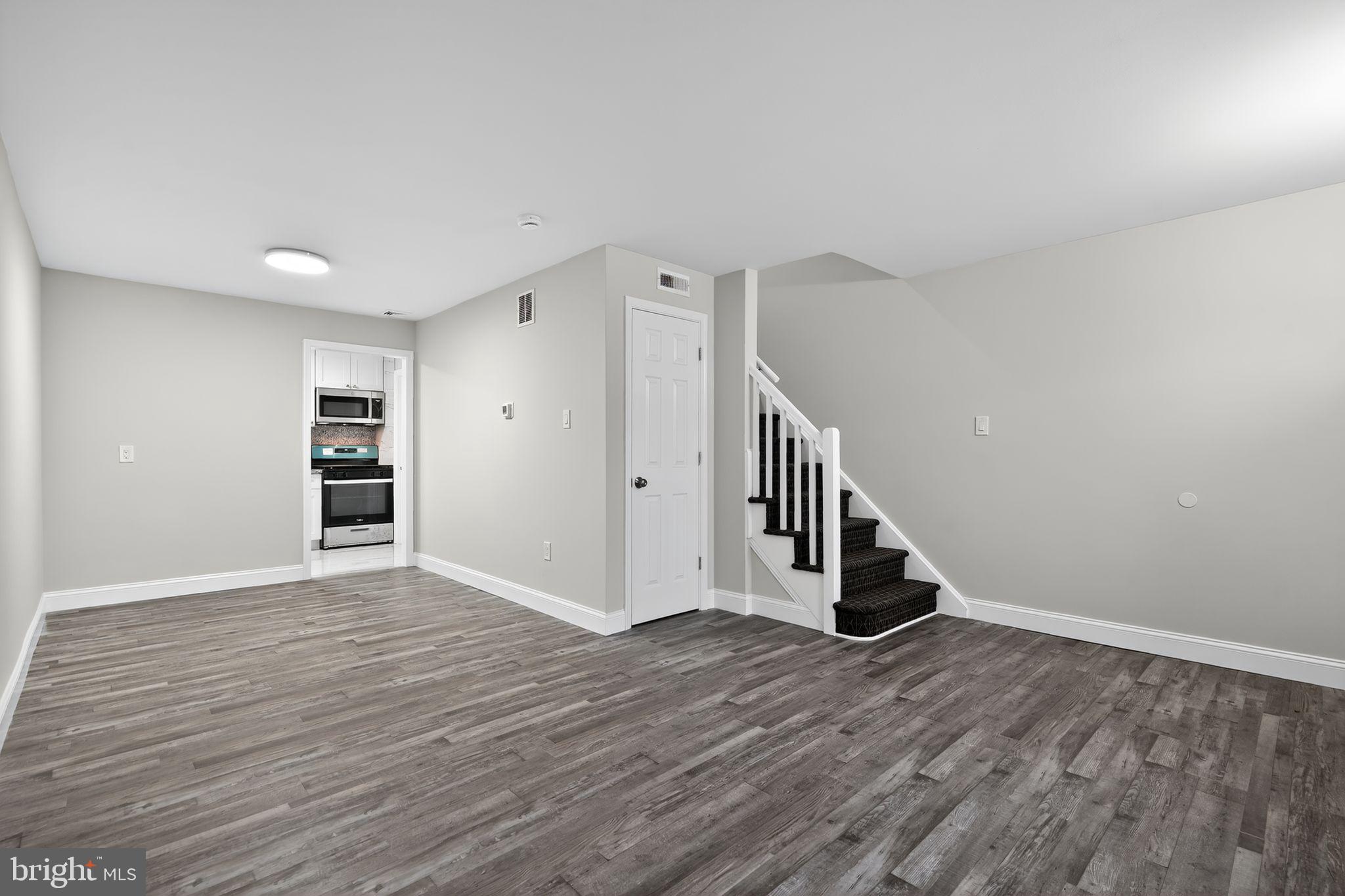 5706 Mitchell Road Levittown, PA 19057 - Photo 5 of 19 a view of an empty room with wooden floor and stairs