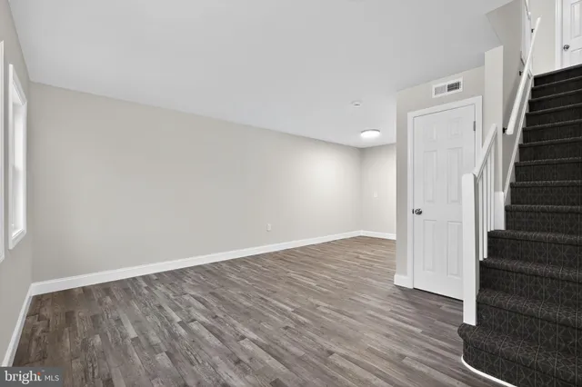 a view of an empty room with wooden floor and stairs