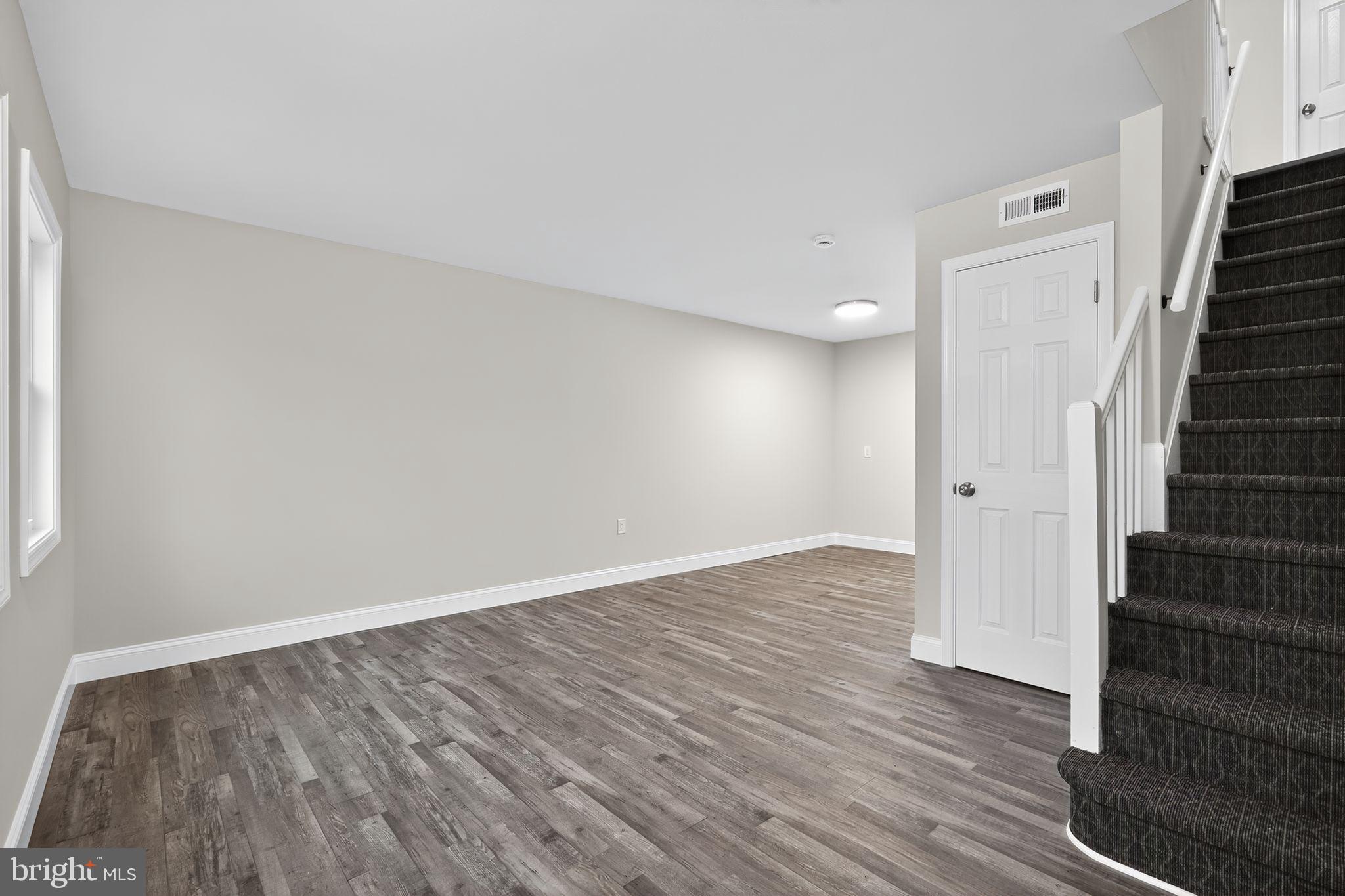 5706 Mitchell Road Levittown, PA 19057 - Photo 7 of 19 a view of an empty room with wooden floor and stairs