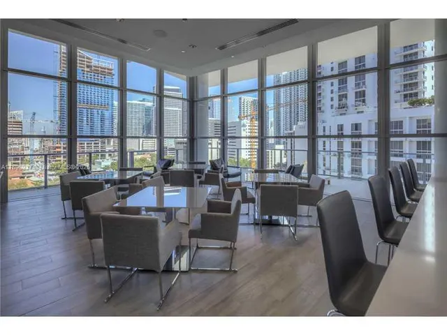 a living room with furniture floor to ceiling windows and wooden floor