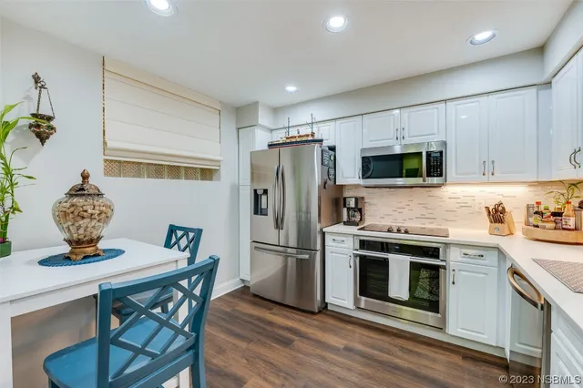 a kitchen with stainless steel appliances a dining table chairs stove refrigerator and microwave