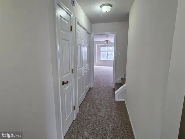 a view of a hallway with white walls and stairs