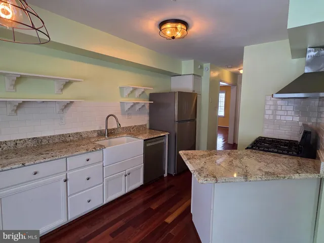 a kitchen with granite countertop a sink a stove and refrigerator
